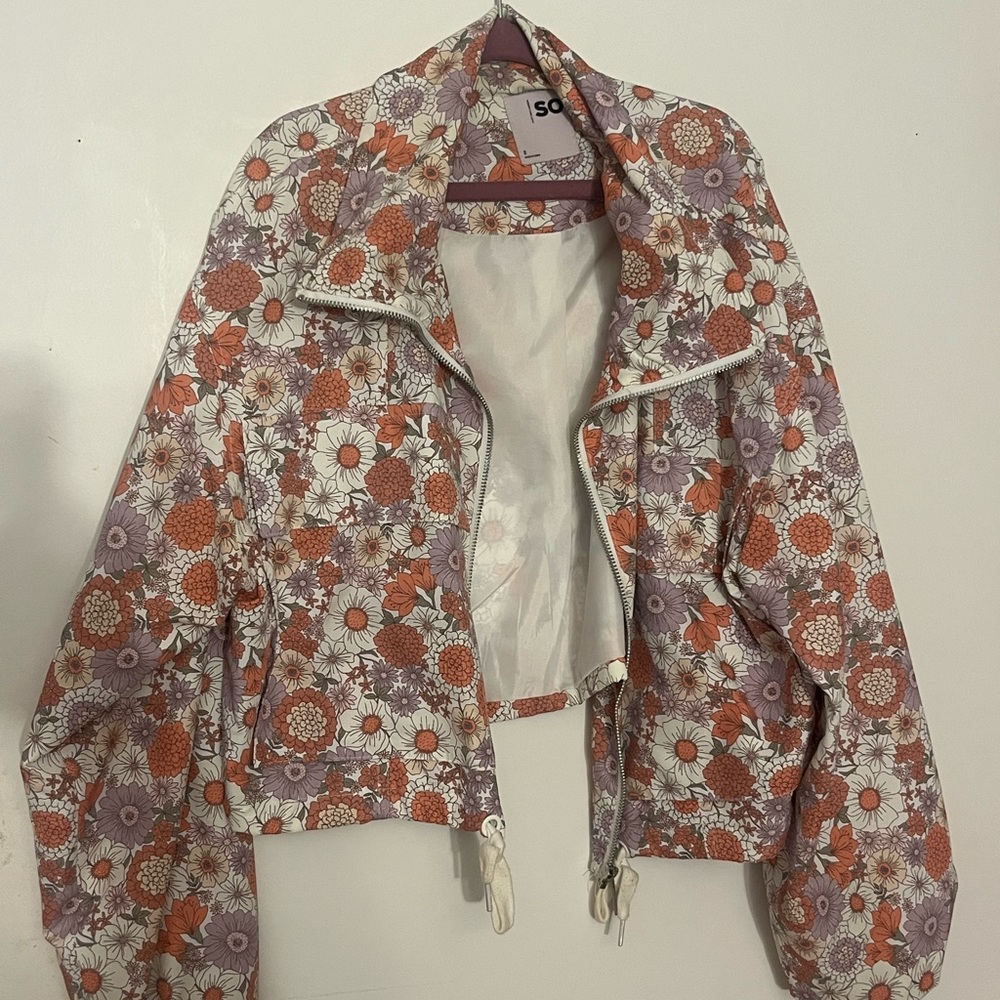 Floral cropped jacket with pockets and cinched waist.